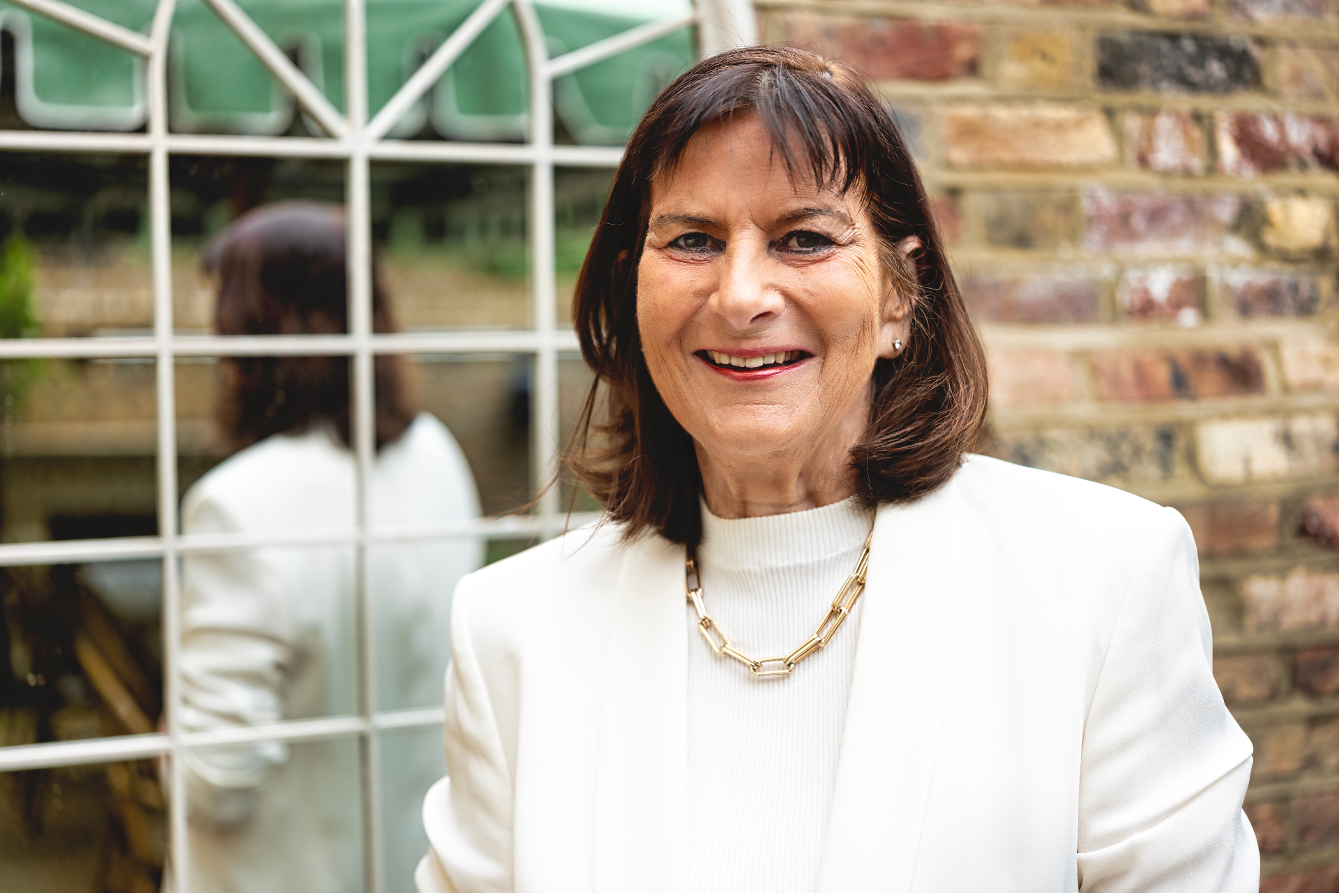 Portrait of Victoria Tomlinson smiling outdoors in a white blazer